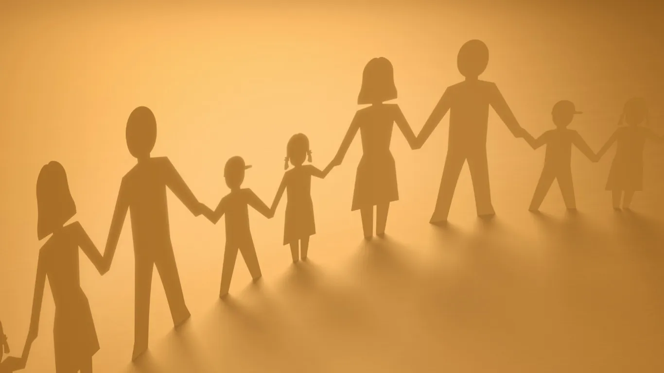 Papierfiguren einer Familie, die sich in warmem Licht an den Händen halten
